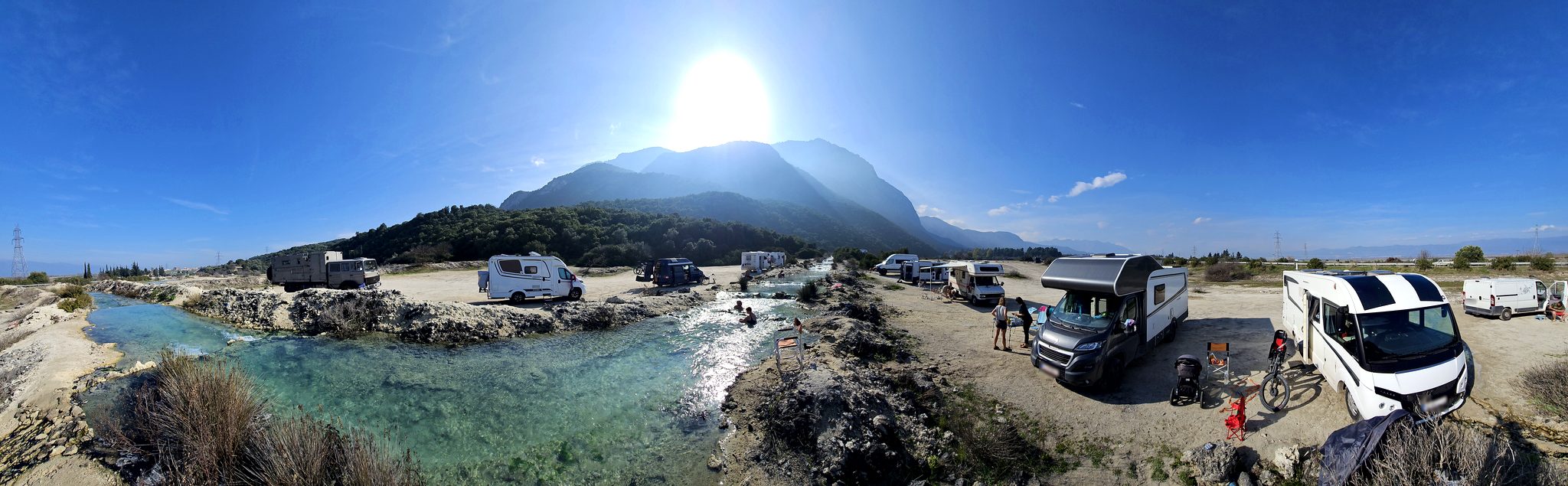 Motorhomes lined up along the Thermopylae hot springs river below the mountains
