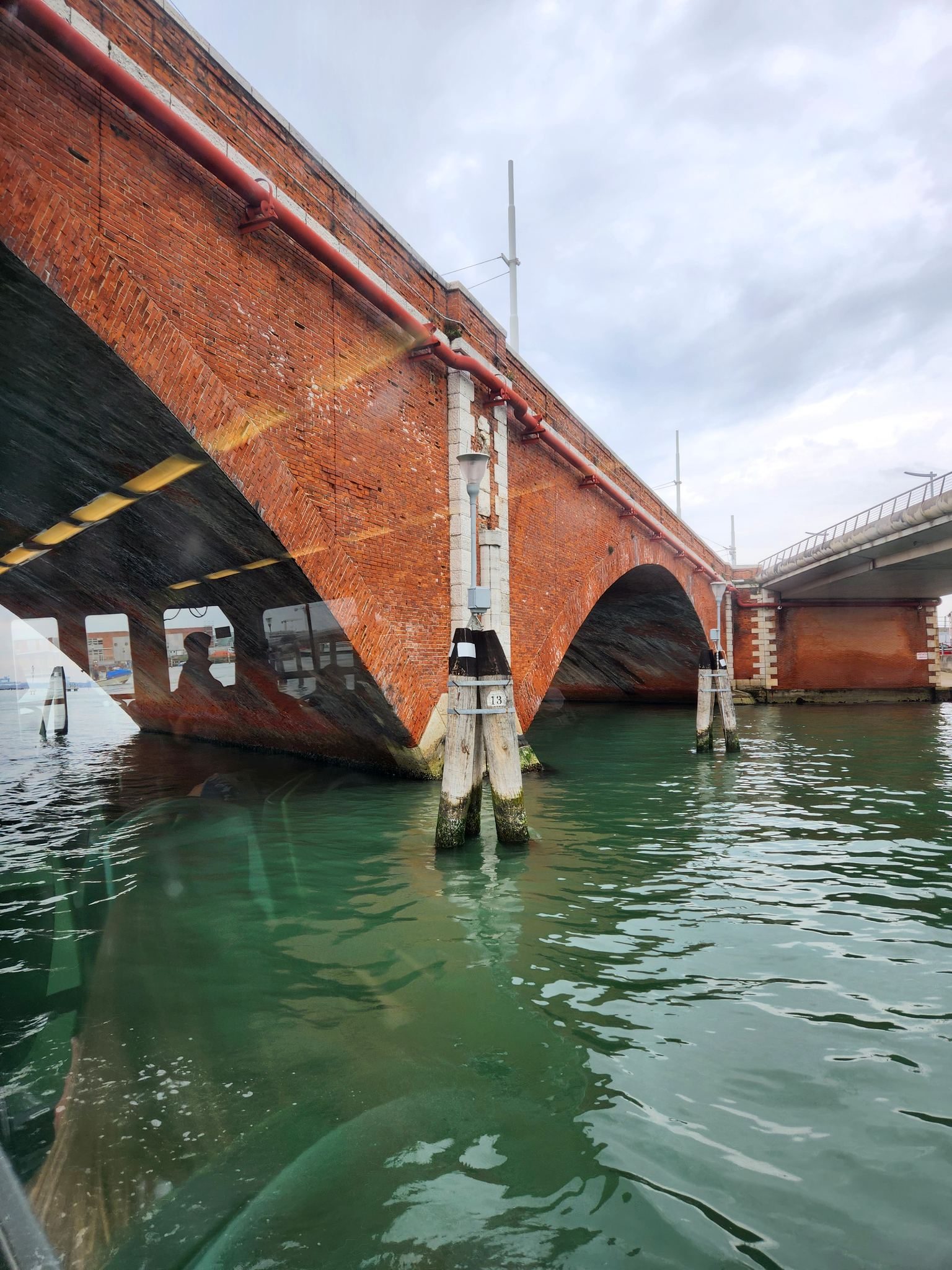 Brick bridge over a green Venetian canal